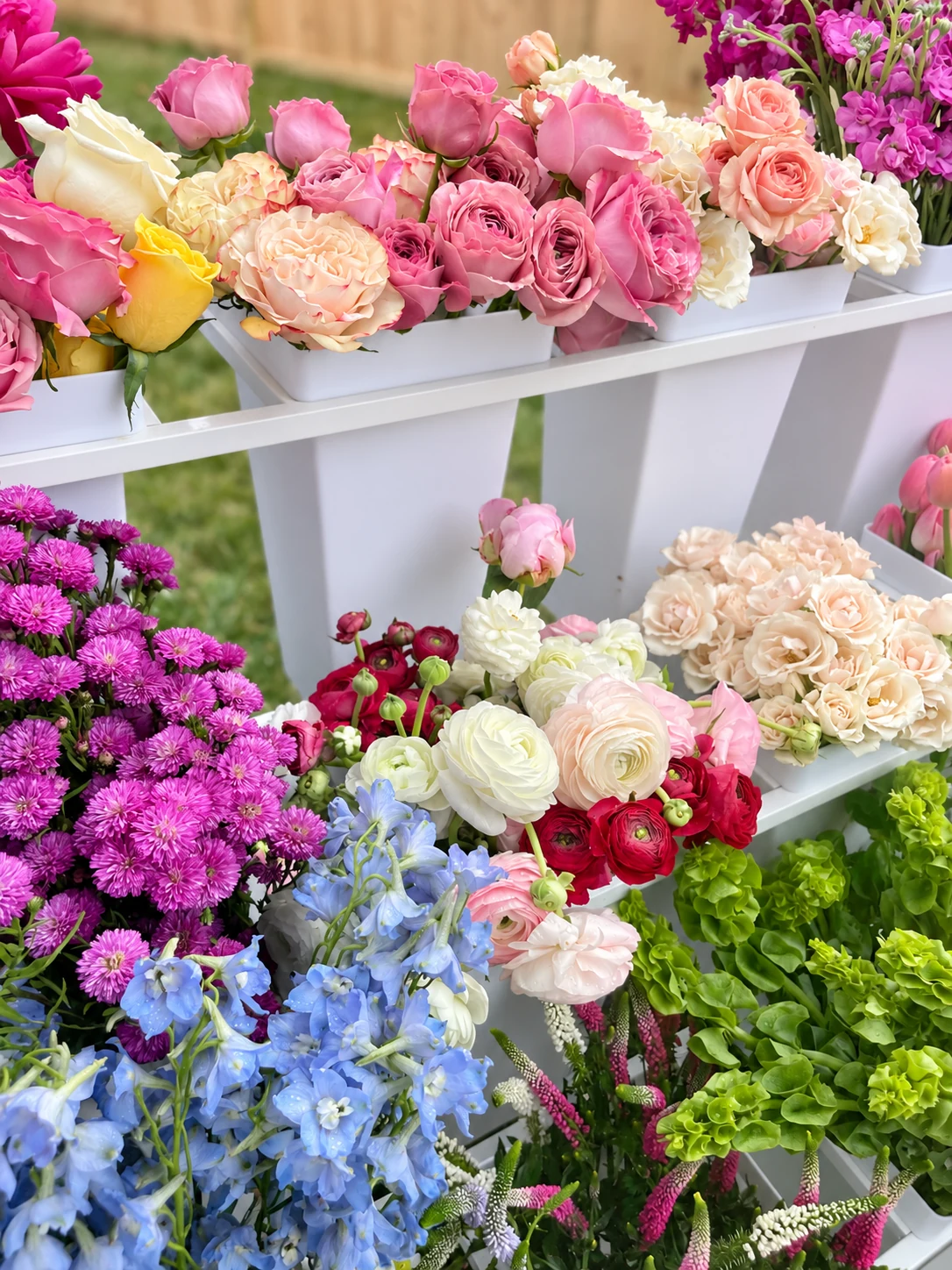 A flower bar filled with pink roses, ranunculus and blue delphinium